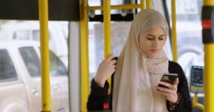 A young hijabi reading her smartphone on the bus