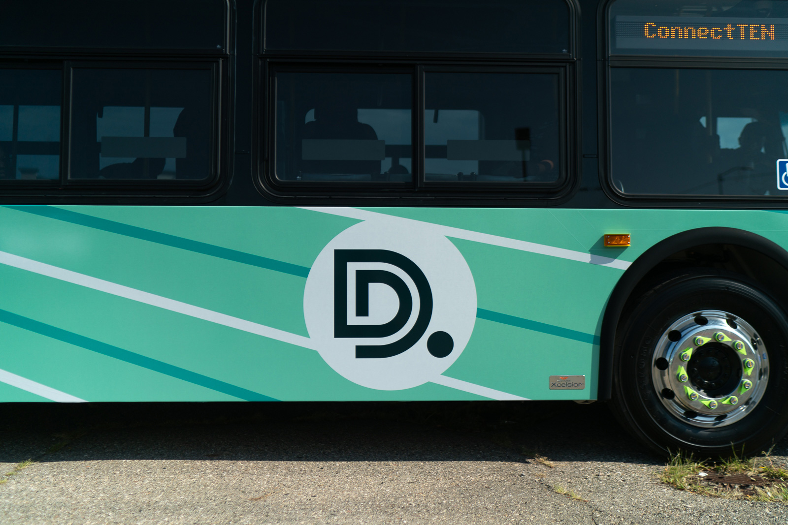 A photo of the side of a new DDOT bus, showing the logo with green lines behind it.