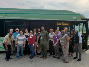 TRU staff, supporters, and DDOT staff pose in front of a new, green bus that says SHOE TERMINAL on its destination sign. Everyone is smiling.