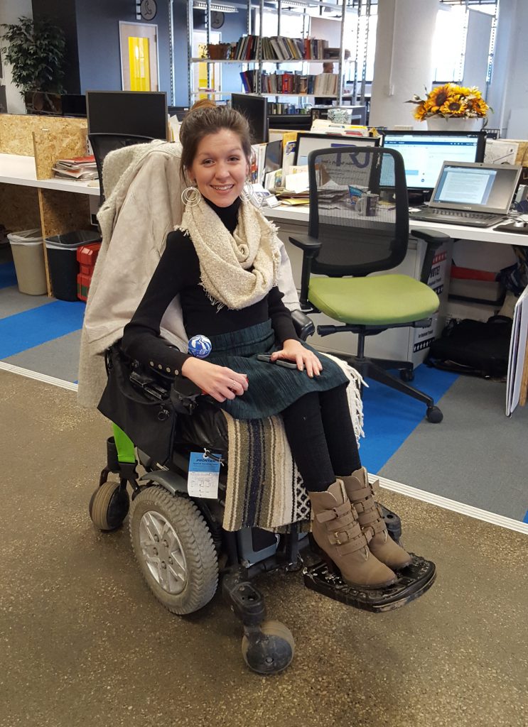 Kristen in her power wheelchair working at the TRU office