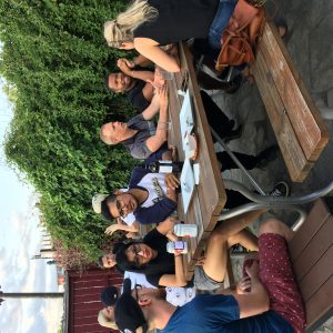 A diverse group of people talking with each other around a picnic table on a patio