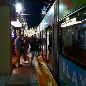 Group of people getting on Qline at Campus Martius at night.