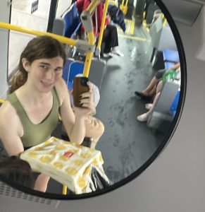 Woman taking photo in the mirror on a bus, soaking wet from rain.