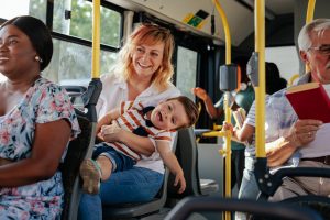 Mom and son sitting on the bus, looking happy surrounded by others