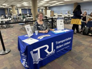 Deb sitting at a TRU table with flyers, handouts, and info.