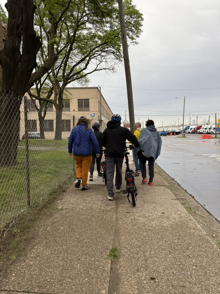 Group and person with bicycle walking on sidewalk