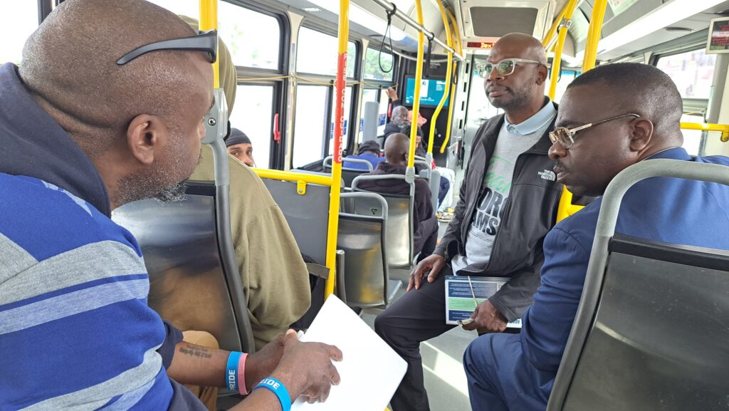 A candidate rides the bus with TRU and transit activist Brother Cunningham.