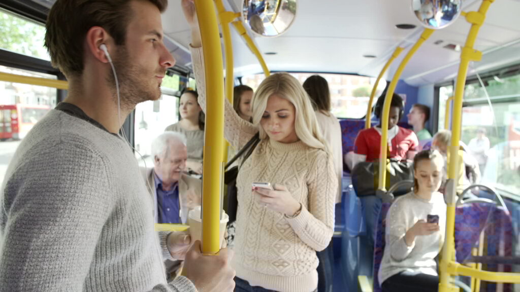 Woman looking at phone on crowded bus.