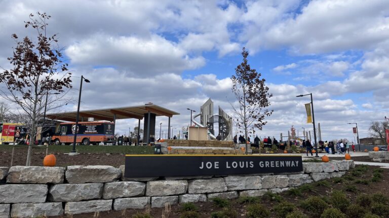 Trailhead for the Joe Louis Greenway during October, full of people and decorated with pumpkins