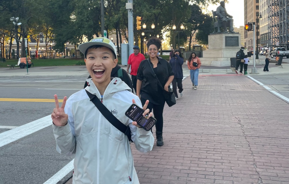 Smiling Civic Academy attendees in a crosswalk in downtown Detroit, with a statue of Detroit Mayor Hazen Pingree behind them.