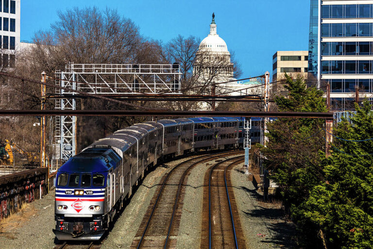 The US Capitol building from a nearby rail line, with a passenger train traveling down the tracks